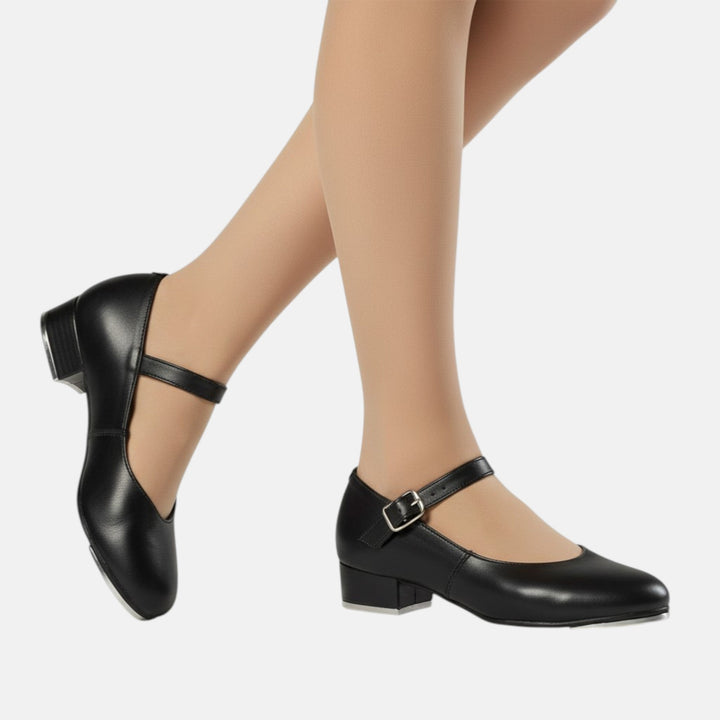 Black shoes with a block heel worn by a person on a white background