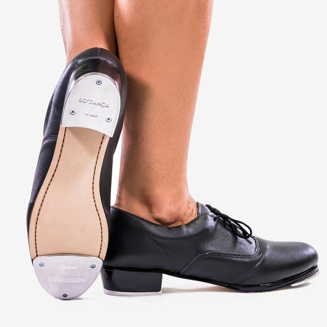 Black tap dance shoes with white soles on a light gray background