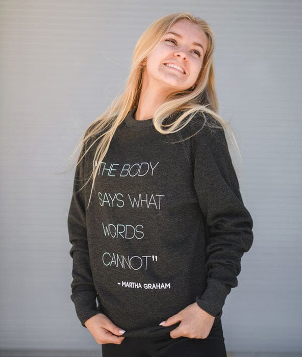 Woman wearing a black sweatshirt with a quote on it against a gray background