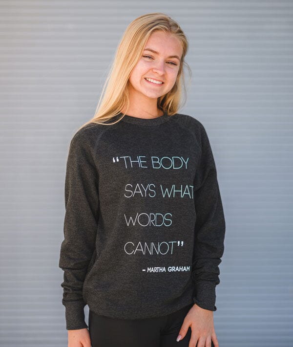 Person wearing a dark gray sweatshirt with a quote by Martha Graham against a gray background