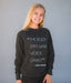 Person wearing a dark gray sweatshirt with a quote by Martha Graham against a gray background