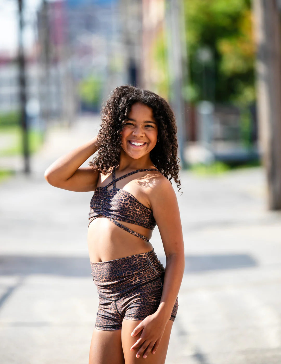 Young woman in a brown lace outfit standing on a street with blurred background