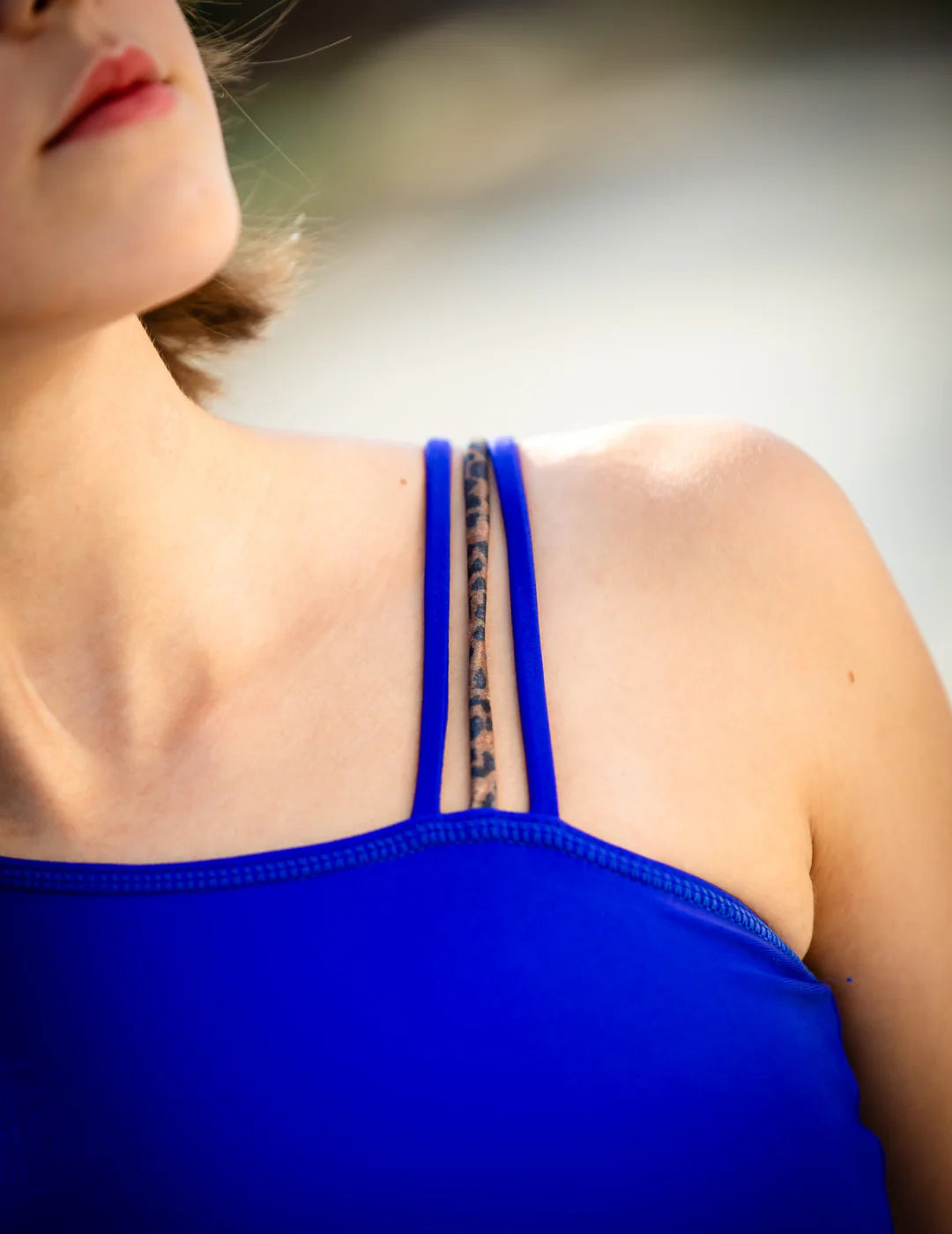 Close-up of a person wearing a blue top with thin straps.