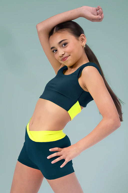 Young girl in a green and yellow sports outfit posing against a gray background
