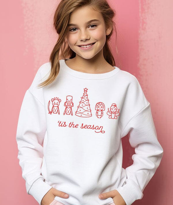 Young girl wearing a white sweatshirt with red Christmas-themed graphics and text on a pink background