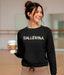 Woman wearing a black sweatshirt with 'BALLERINA' text, holding a coffee cup.