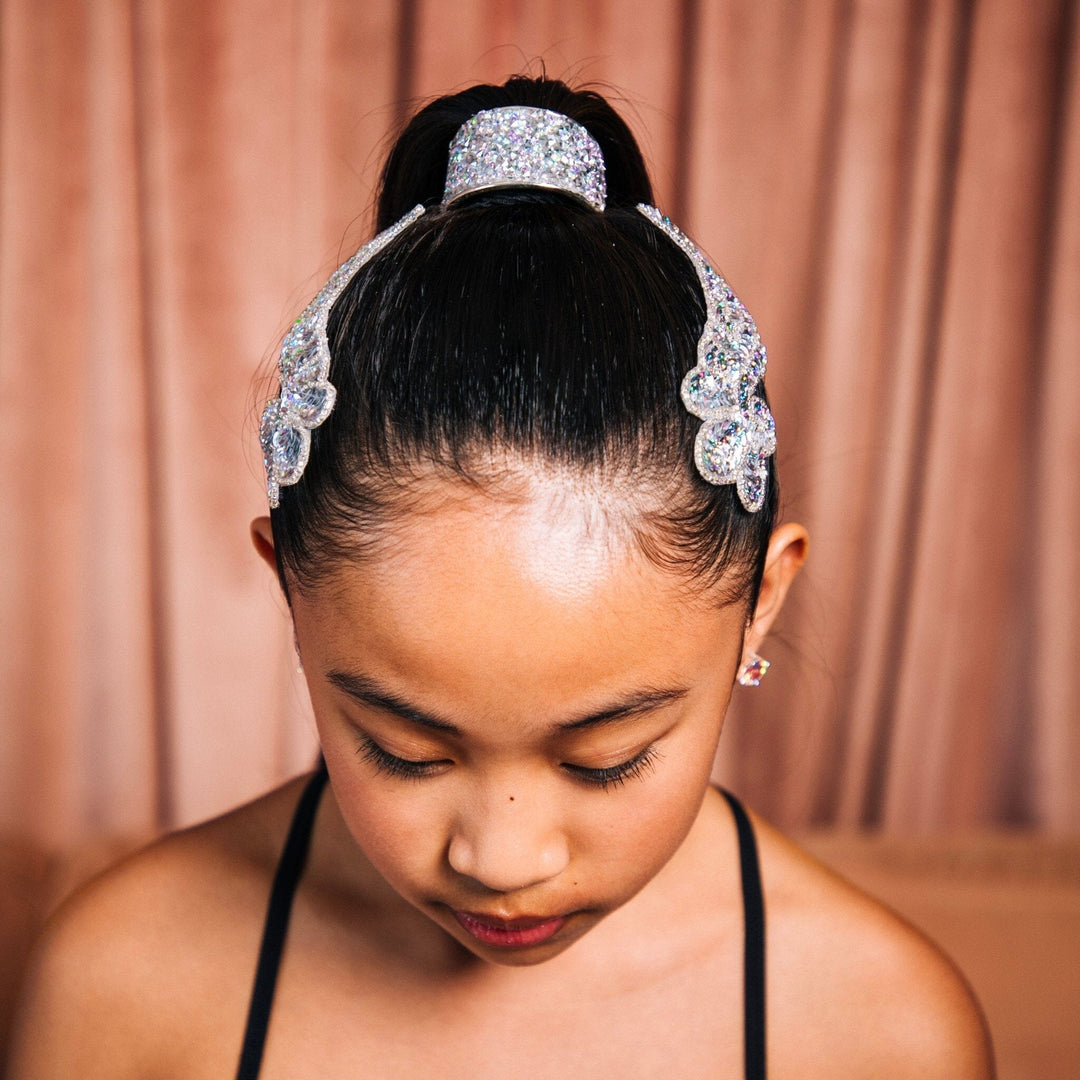 Young girl wearing a sparkling headband against a pink curtain background