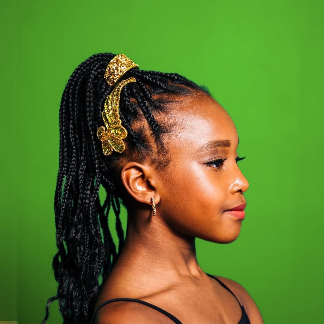 Profile of a young girl with braided hair wearing a decorative headband against a green background