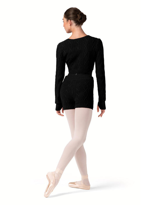Ballerina in a black long-sleeve top and beige tights on a white background