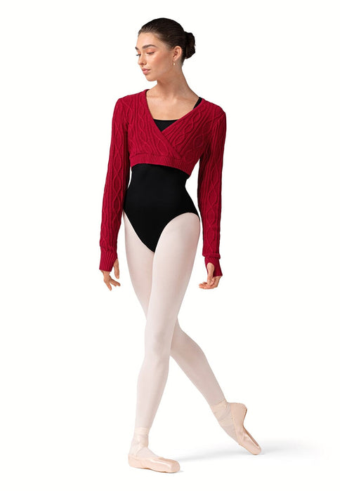 Dancer wearing a red long-sleeve top, black leotard, and beige tights on a white background