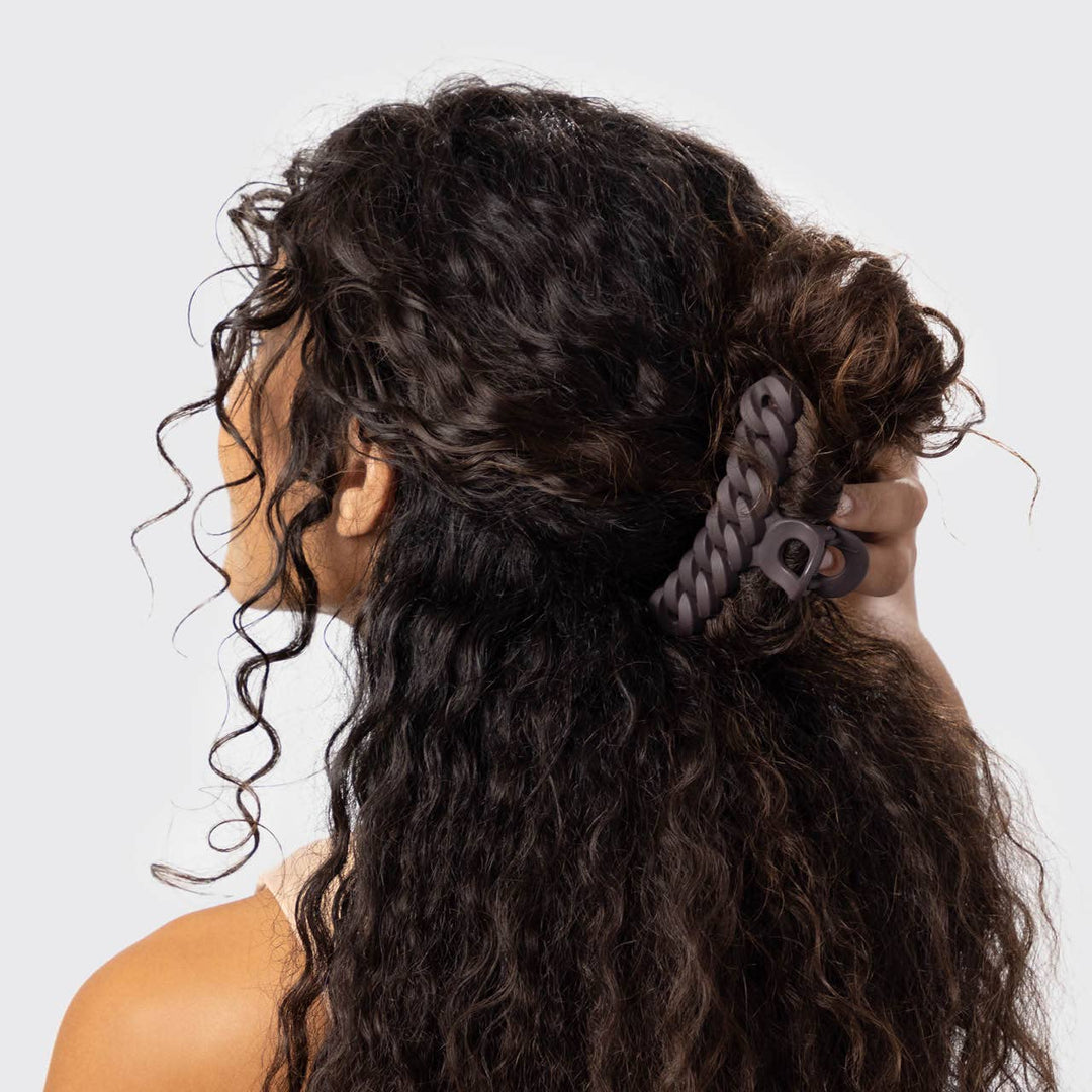 Woman with styled hair featuring a decorative hair accessory on a plain background
