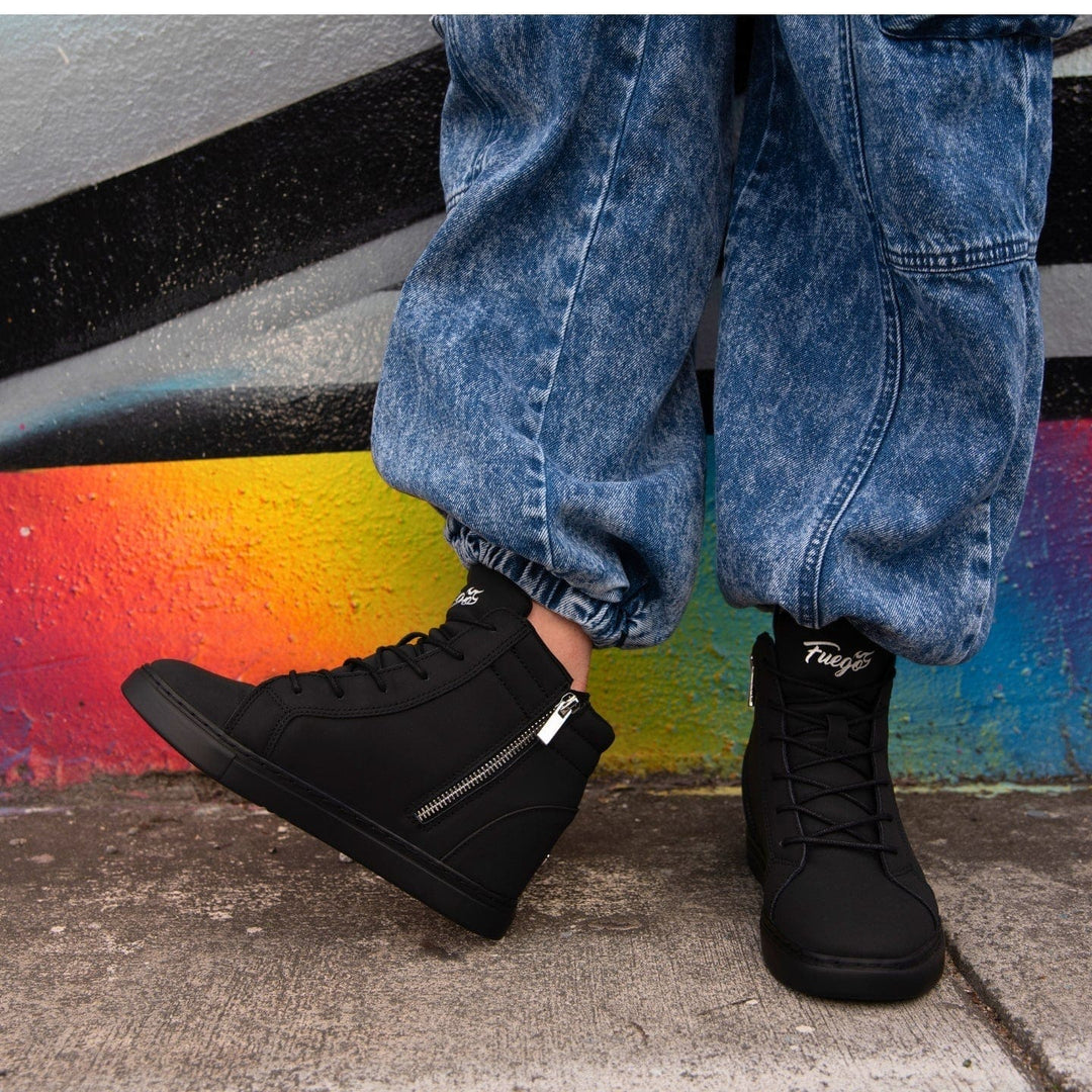 Black high-top sneakers with zippers on a background of blue jeans and colorful street art.