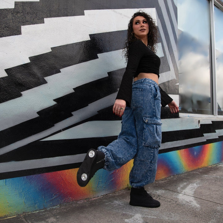 Person posing against a colorful wall with geometric patterns.