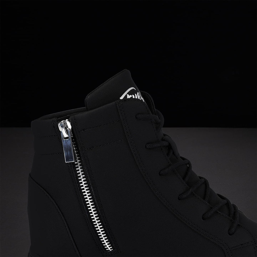 Black high-top sneaker with silver zipper on a dark background