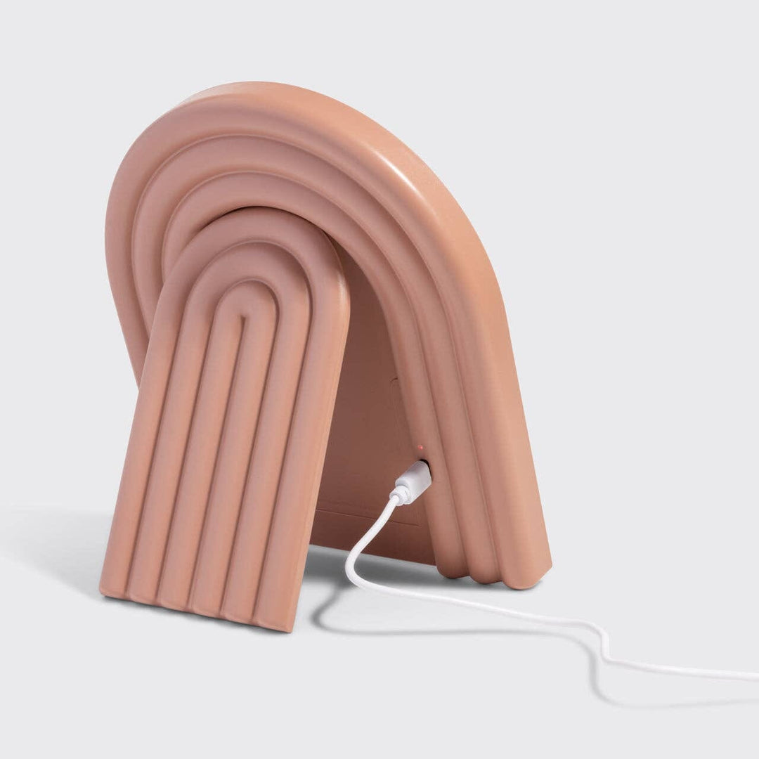 Pink, wave-like lamp with a white cord on a light gray background
