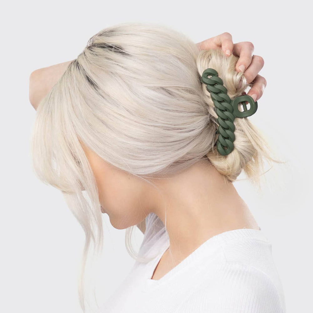 Person with blonde hair tied with a green hair tie against a white background