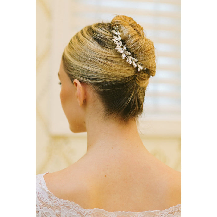 Woman with styled hair and a decorative headband against a neutral background