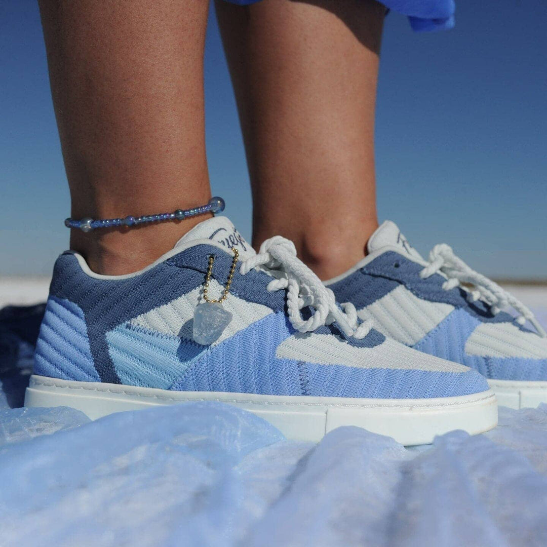 Blue and white sneakers worn on a salt flat with clear blue sky