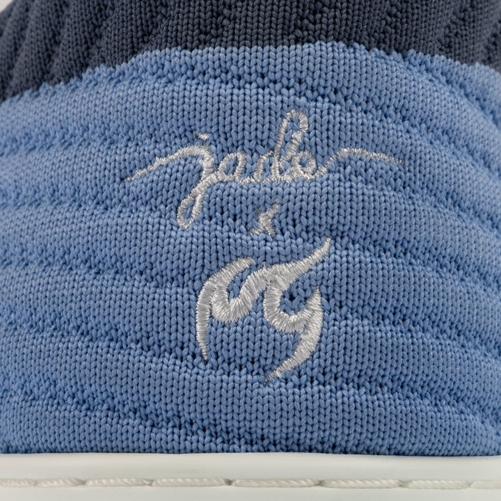 Close-up of a blue textured fabric with embroidered text on a white background