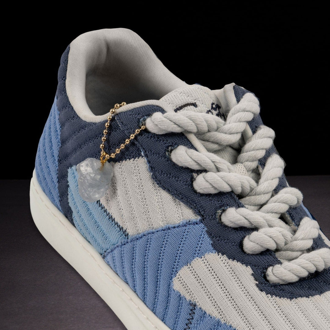 Blue and gray sneaker with braided laces on a dark background
