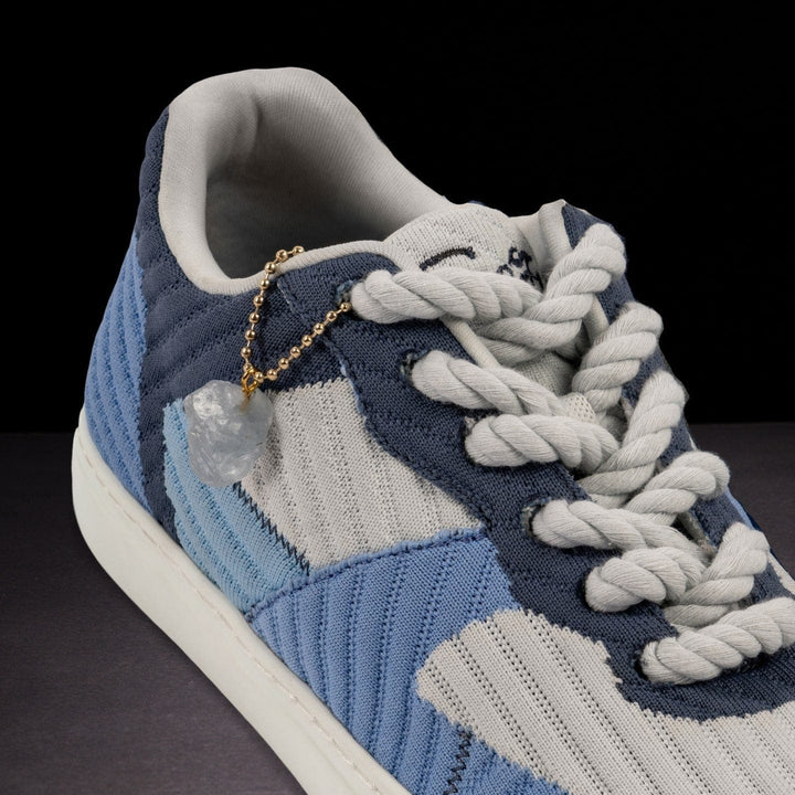Blue and gray sneaker with braided laces on a dark background