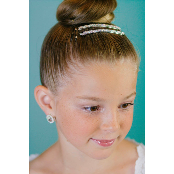 Young girl with a bun hairstyle wearing a headband against a teal background