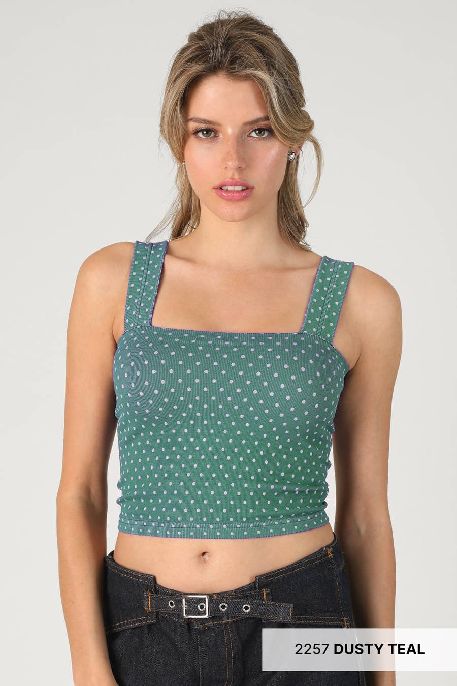 Woman wearing a green polka dot crop top against a plain background
