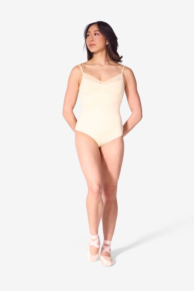 Woman wearing a light yellow bodysuit on a white background