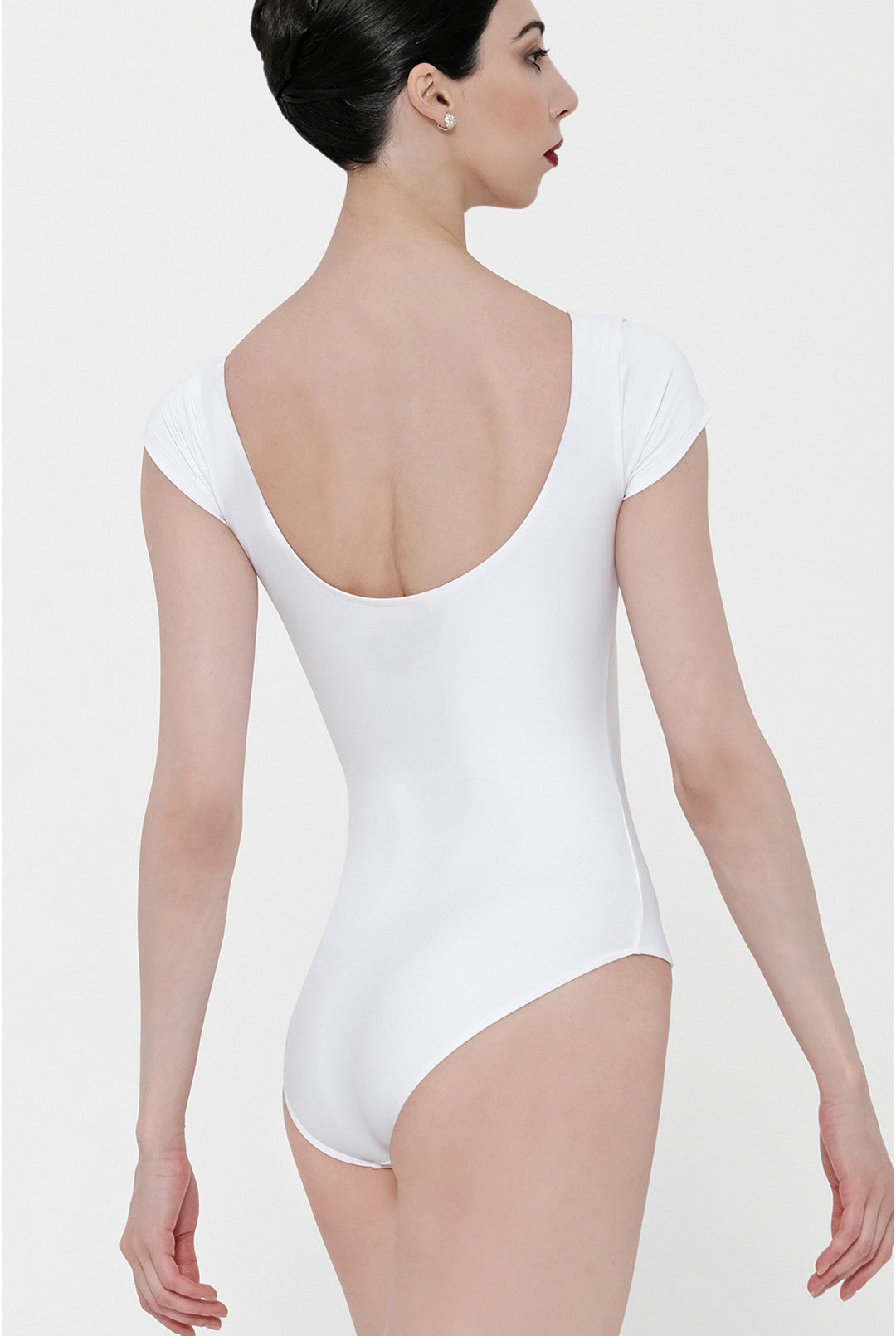 A woman shown from the back wearing a white short-sleeve bodysuit with a deep scoop neckline, photographed against a plain light gray studio background.