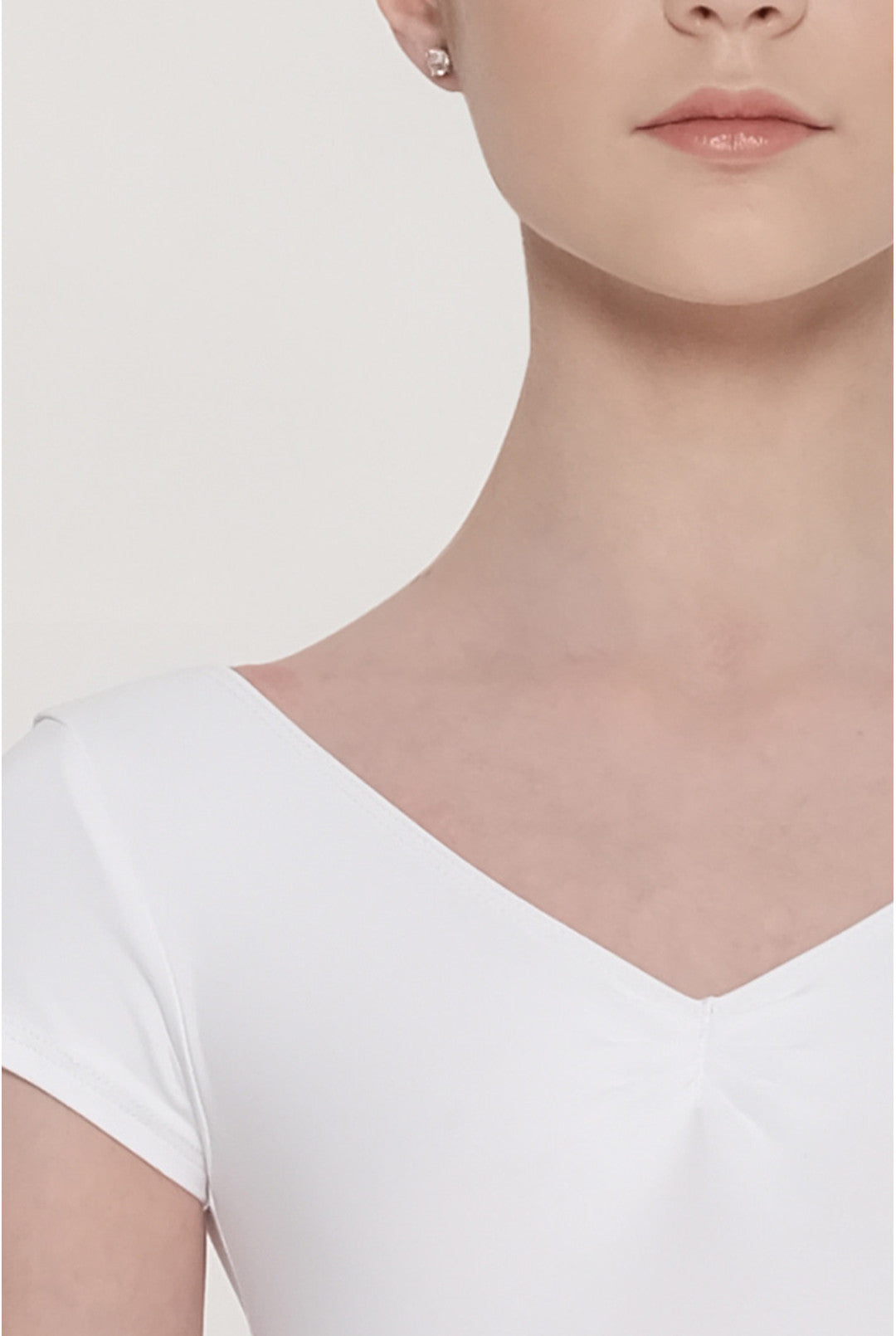 Close-up of a model wearing a white short-sleeve V-neck top, showing the neckline and shoulder details against a plain light background.