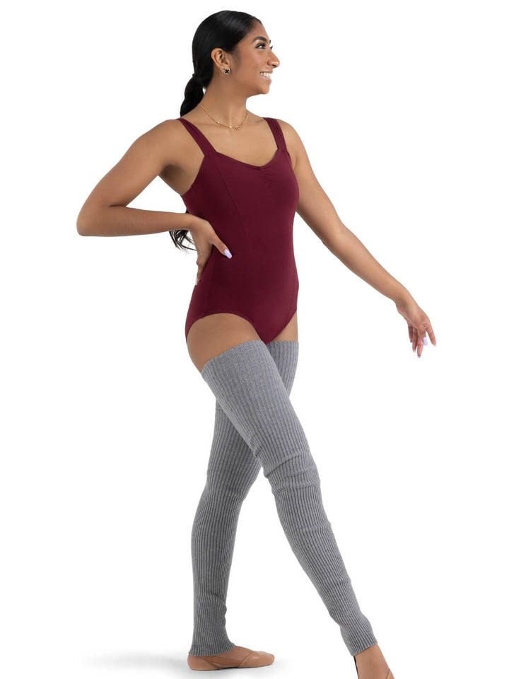 Woman wearing a maroon leotard and gray knee-high socks on a white background