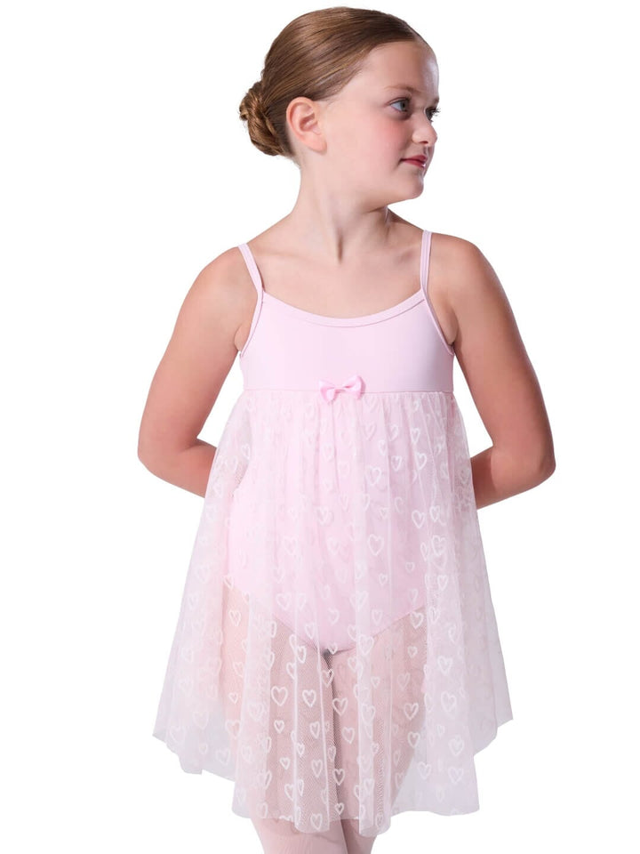 Young girl wearing a light pink dress with heart patterns on a white background