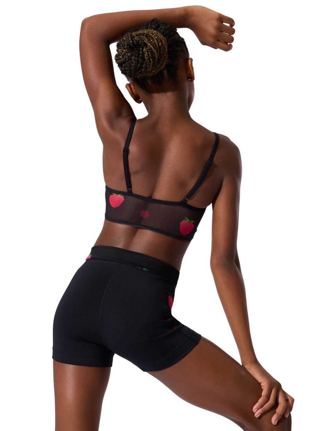 Person wearing a black lingerie set with heart designs on a white background