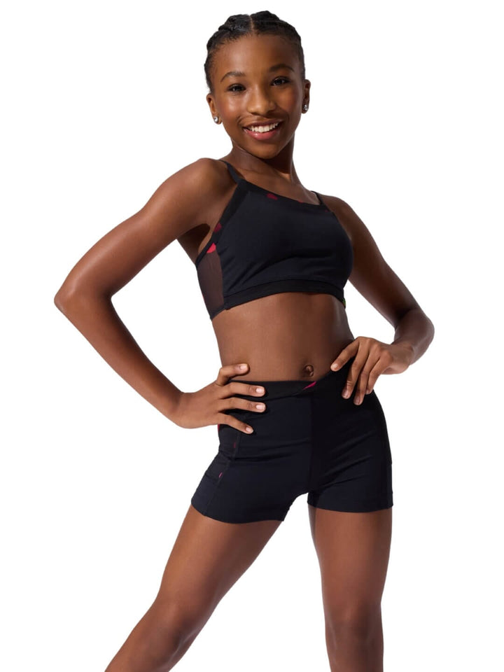 Young woman wearing a black sports bra and shorts on a white background