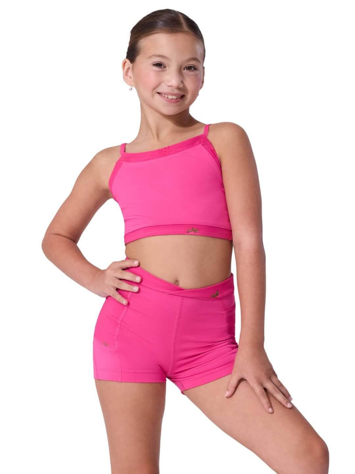 Young girl wearing a pink sports bra and shorts set on a white background