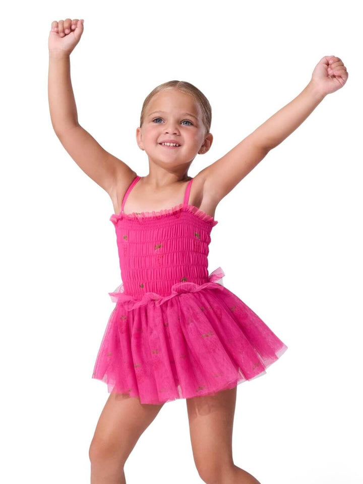 Young girl in a pink ballet dress with arms raised on a white background