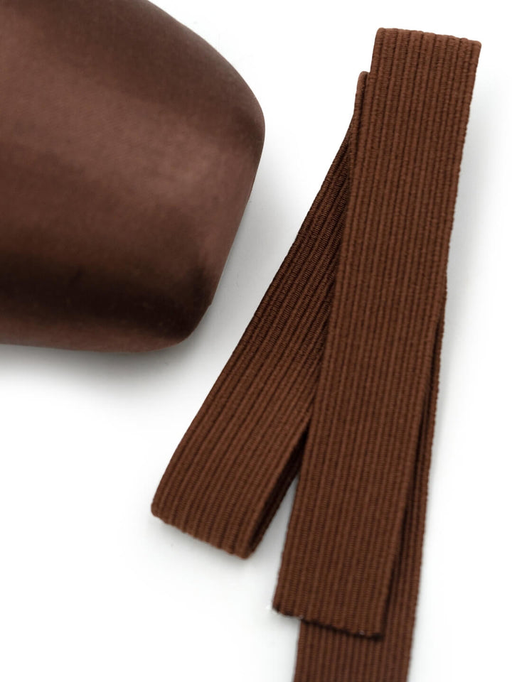 A close-up of a dark brown ribbed knit fabric accessory, showing both a folded cylindrical section and a long narrow strip on a white background.
