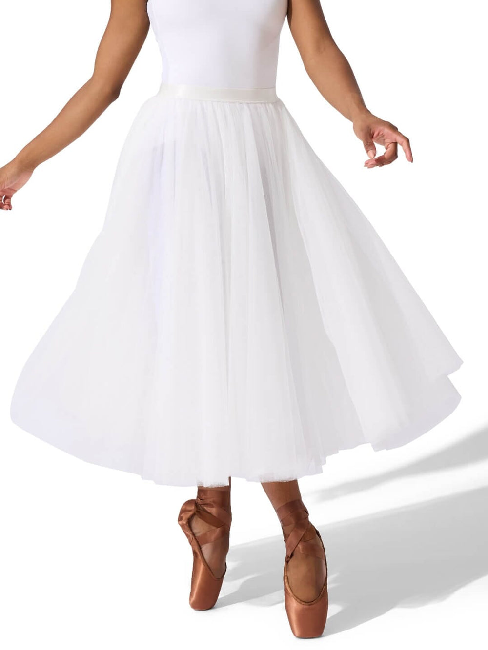 Person wearing a white skirt and brown ballet shoes on a white background