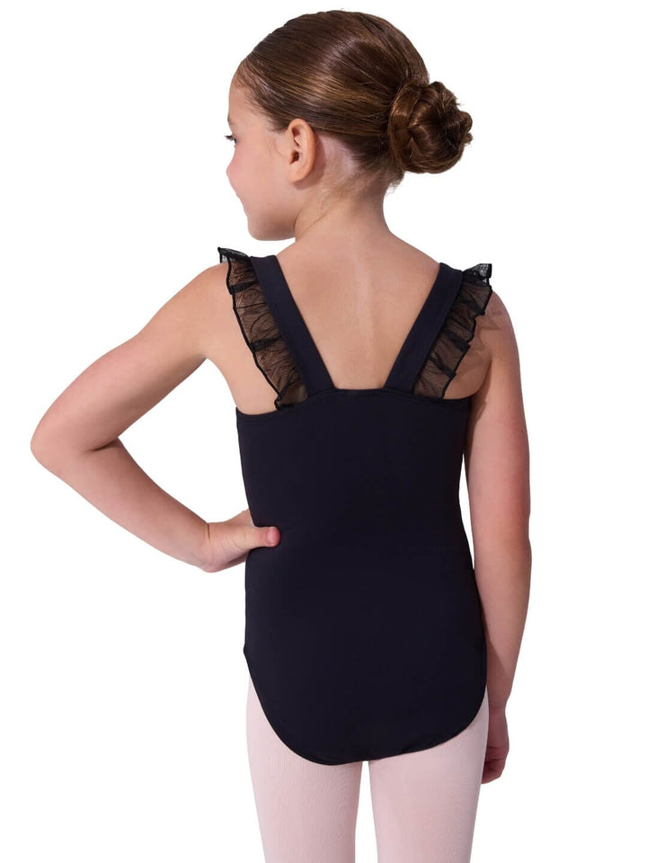 Young girl wearing a black leotard with sheer shoulder details on a white background