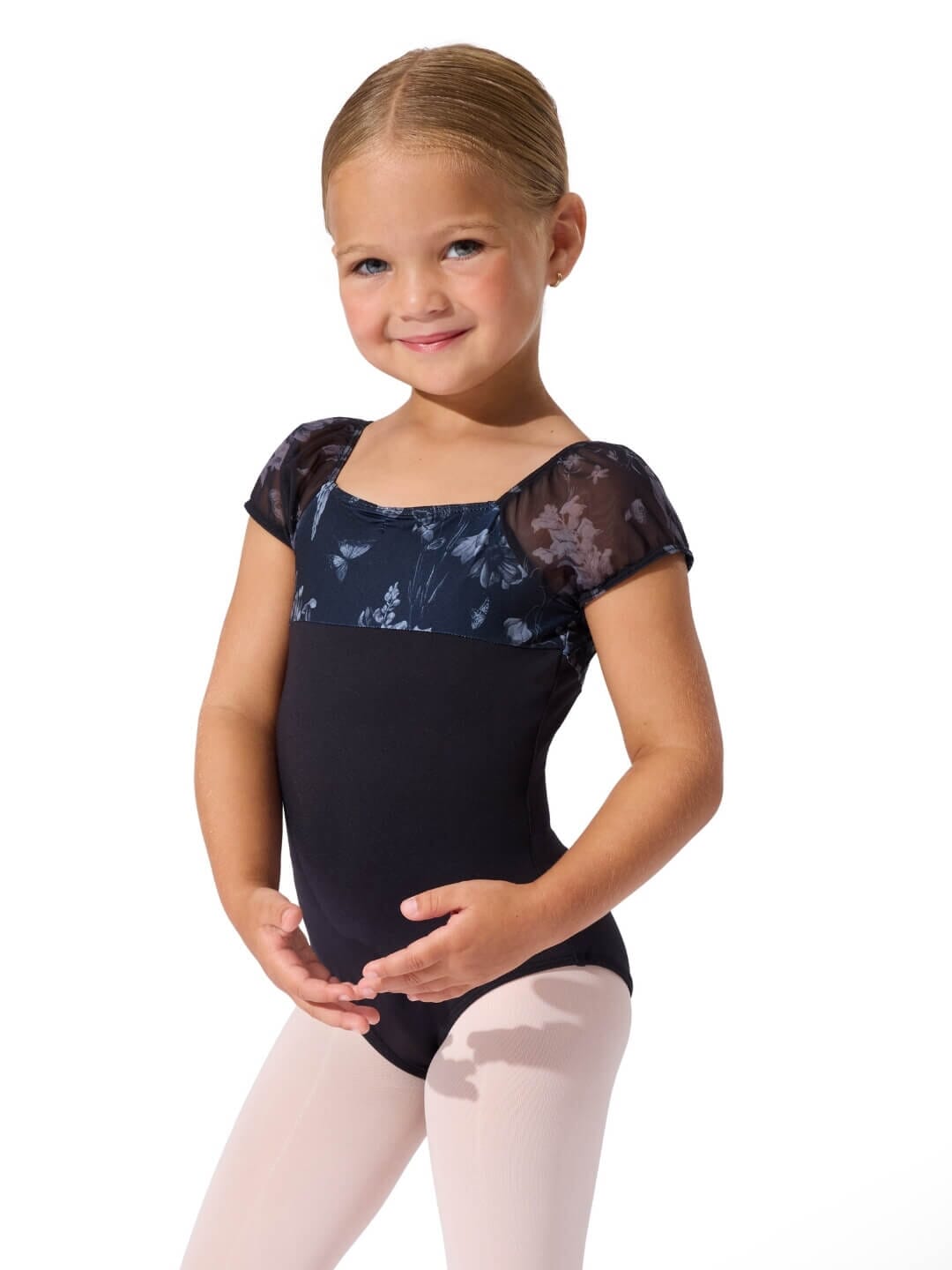 Young girl wearing a black floral cap-sleeve leotard and pink tights on a white background