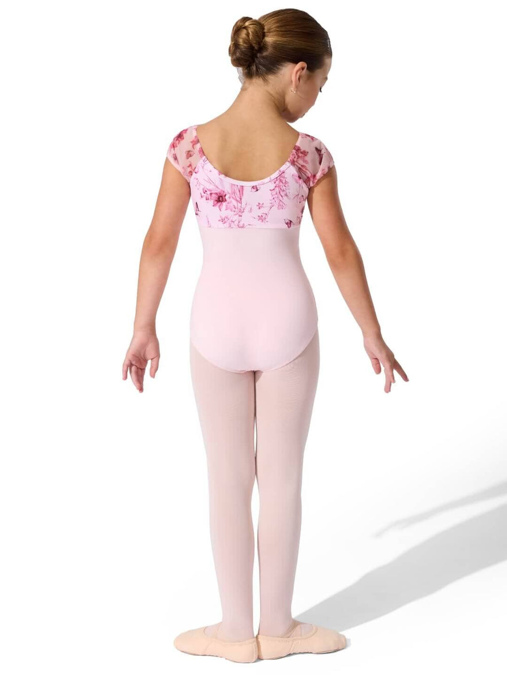 Young girl in a pink floral leotard and tights on a white background