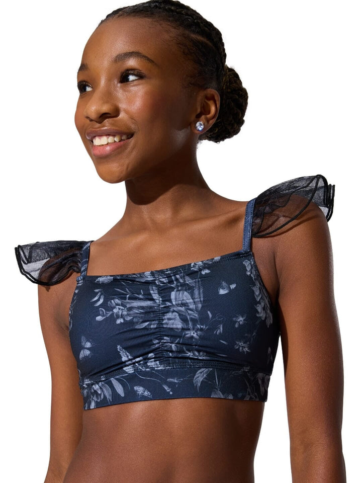 Woman wearing a navy blue floral sports bra with sheer shoulder straps on a white background