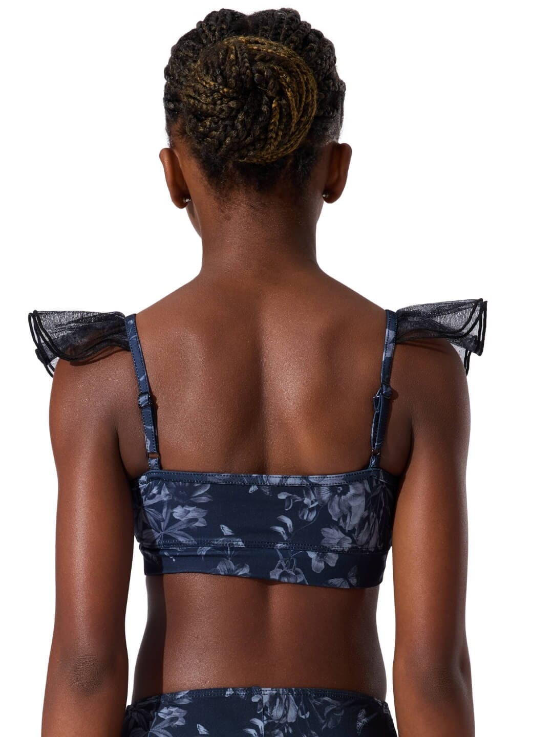 Person wearing a navy floral sports bra with sheer straps on a white background