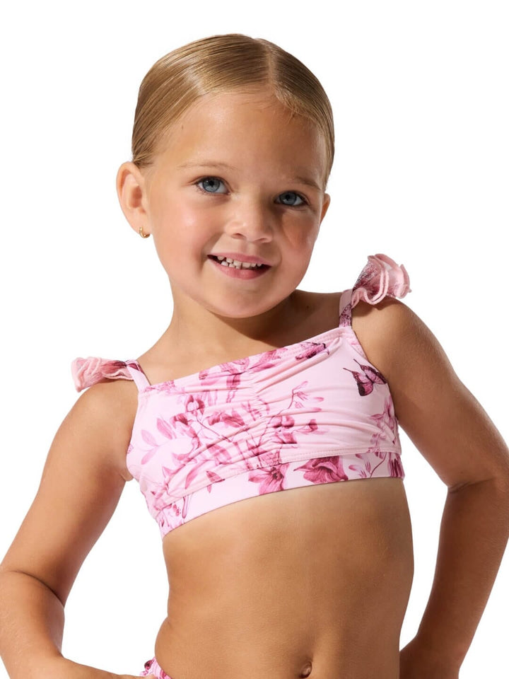 Young girl wearing a pink floral bikini against a white background