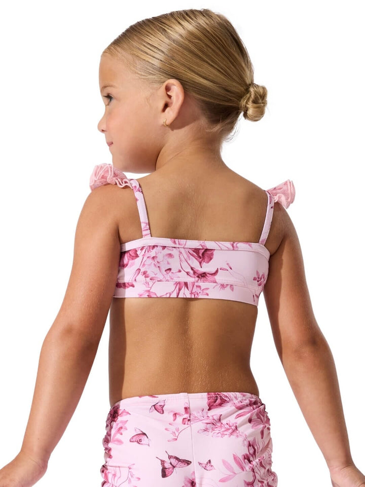 Young girl wearing a pink floral bikini set on a white background