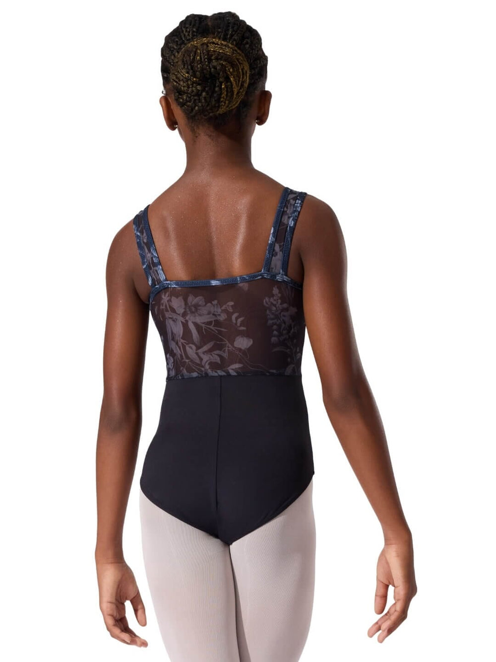 Person wearing a black and floral tank top with beige pants on a white background