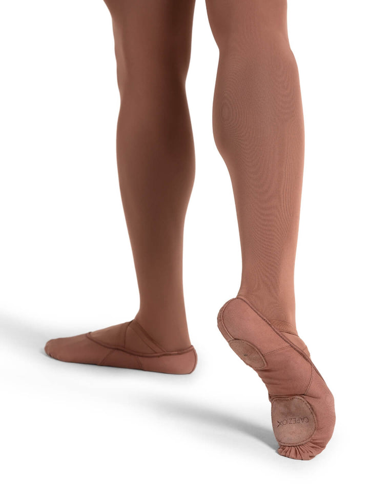 Ballet dancer wearing brown tights and pointe shoes on a white background