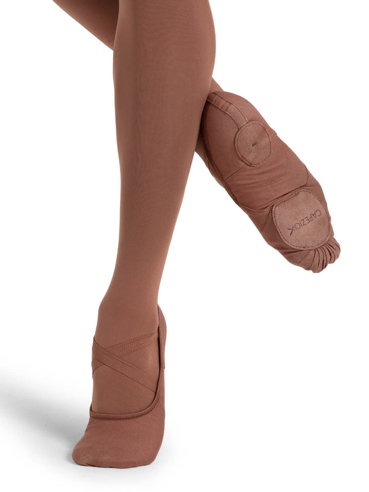 Brown ballet shoes worn with tights on a white background