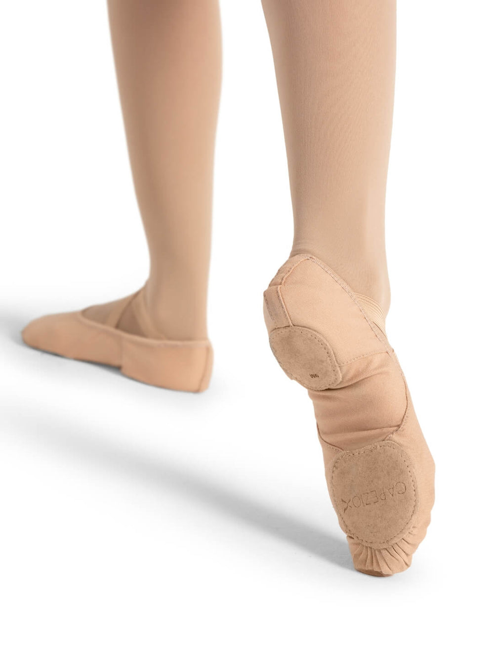Ballet shoes worn with beige tights on a white background
