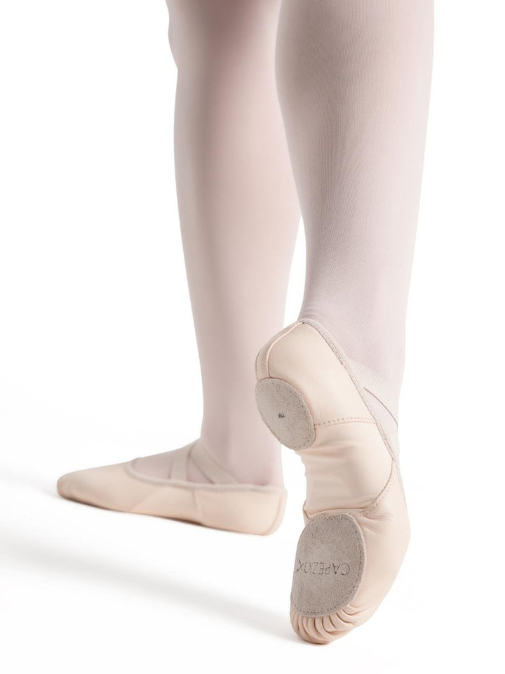 Ballet shoes worn with white tights on a white background